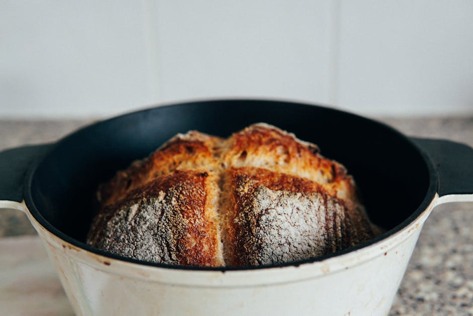 Cast iron Dutch oven with fresh bread on rustic wooden counter with natural sunlight