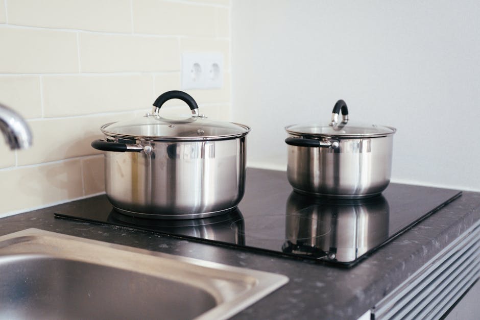 Best Induction Cookware Sets Under $200 in 2026 (Tested & Opinionated) Budget induction cookware set arranged on white kitchen counter with glowing stovetop and natural light