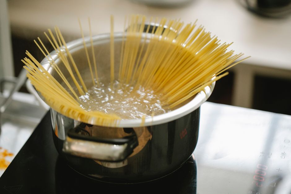 Best Pasta Pot for Boiling: Real Picks That Save Counter Space Three stainless steel pasta pots in various sizes on white kitchen counter with boiling water and fresh herbs.