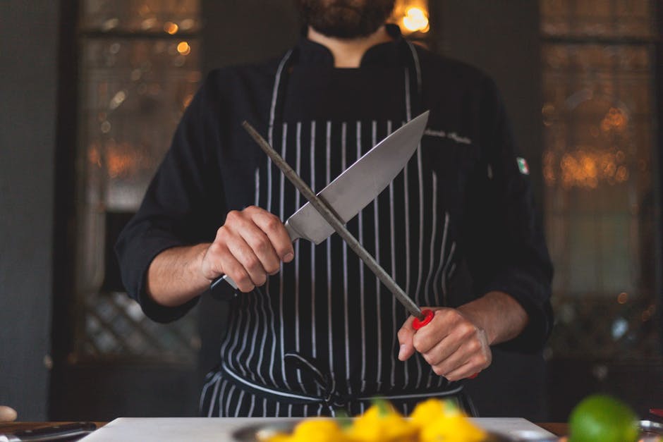 Chef's knife being sharpened on ceramic mug rim on wooden cutting board with natural light