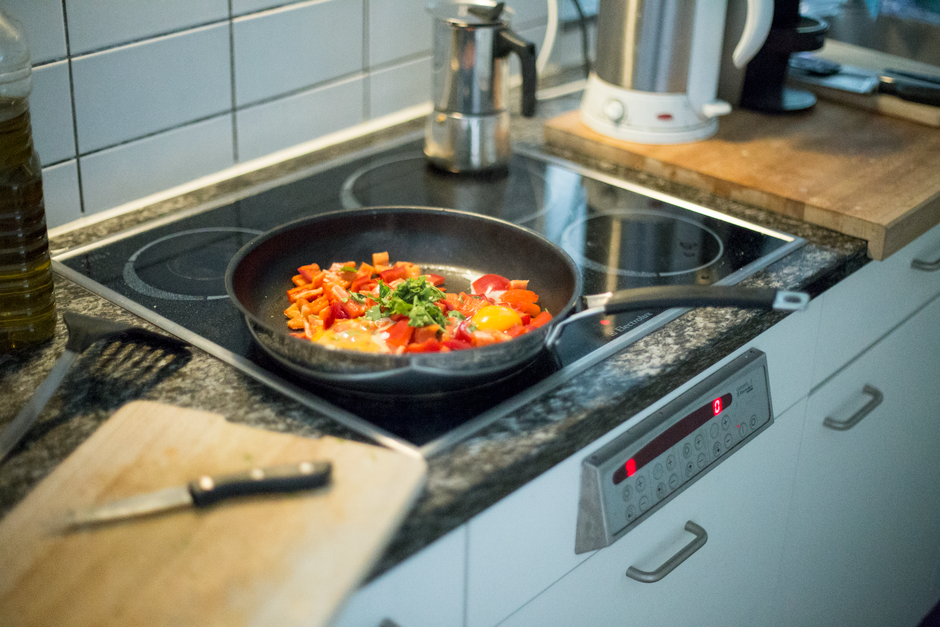 Damaged non-stick wok with peeling coating on electric stovetop in bright kitchen