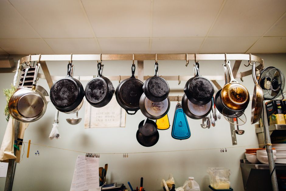 Discolored stainless steel skillet with rainbow tarnish marks on marble countertop next to cleaning cloth